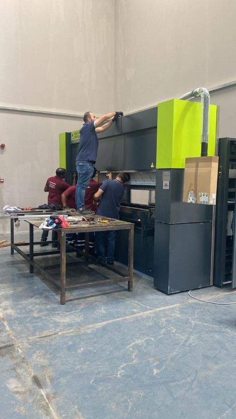 فنيون أثناء تركيب ماكينة الثني CNC وضبط محاذاتها
