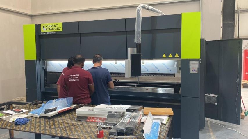 فنيو شركة مصاعد عند ماكينة الثني CNC المستخدمة في تشكيل ألواح الستانلس ستيل للكبائن والإطارات الزخرفية للأبواب